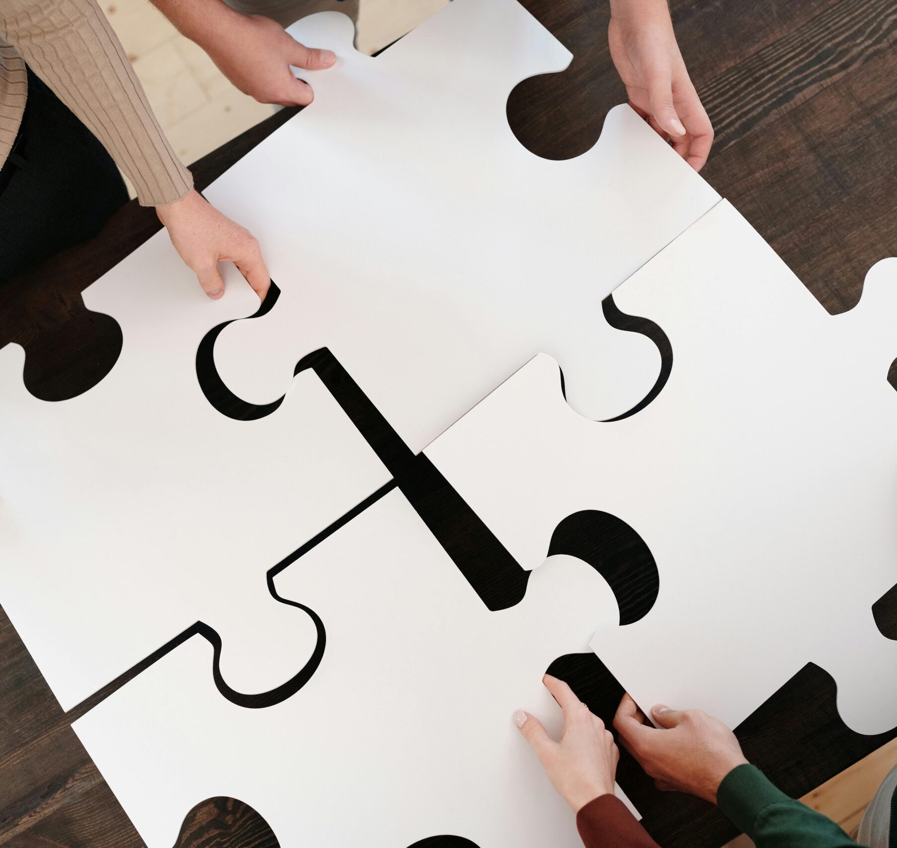 Group collaborating on assembling large puzzle pieces symbolizing teamwork and unity.